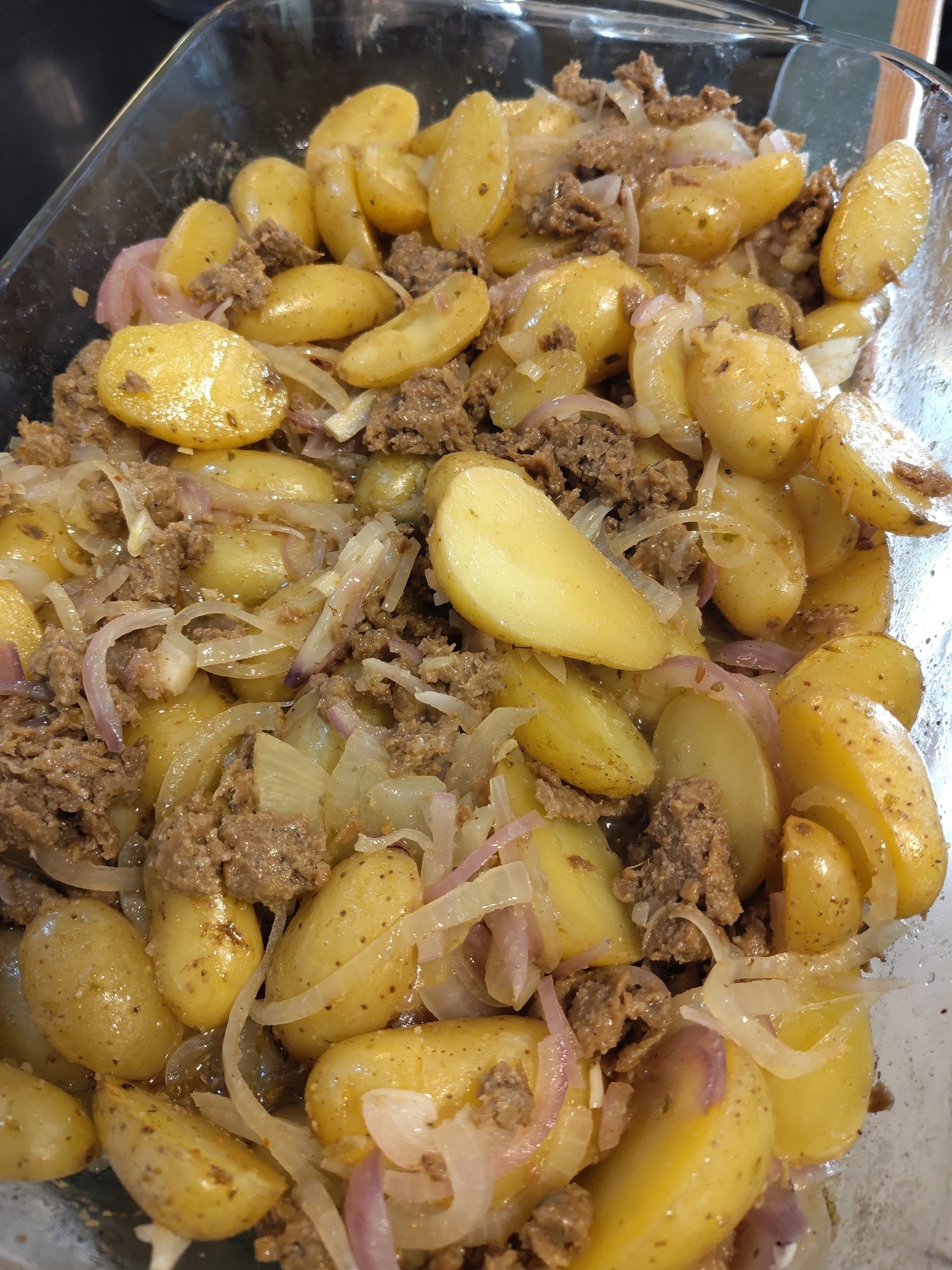 Un plat de pommes de terre tranchées, de #seitan hachée et d’oignons est cuit et assaisonné dans un plat de cuisson en verre.&10;&10;A dish of sliced potatoes, vegeterian seitan, and onions is cooked and seasoned in a glass baking dish.